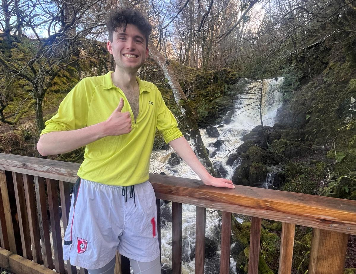 Tomas in training gear on bridge, giving thumbs up