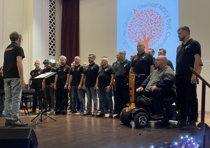 World AIDS Day 2023 vigil with a line of people wearing black on a stage in Cardiff