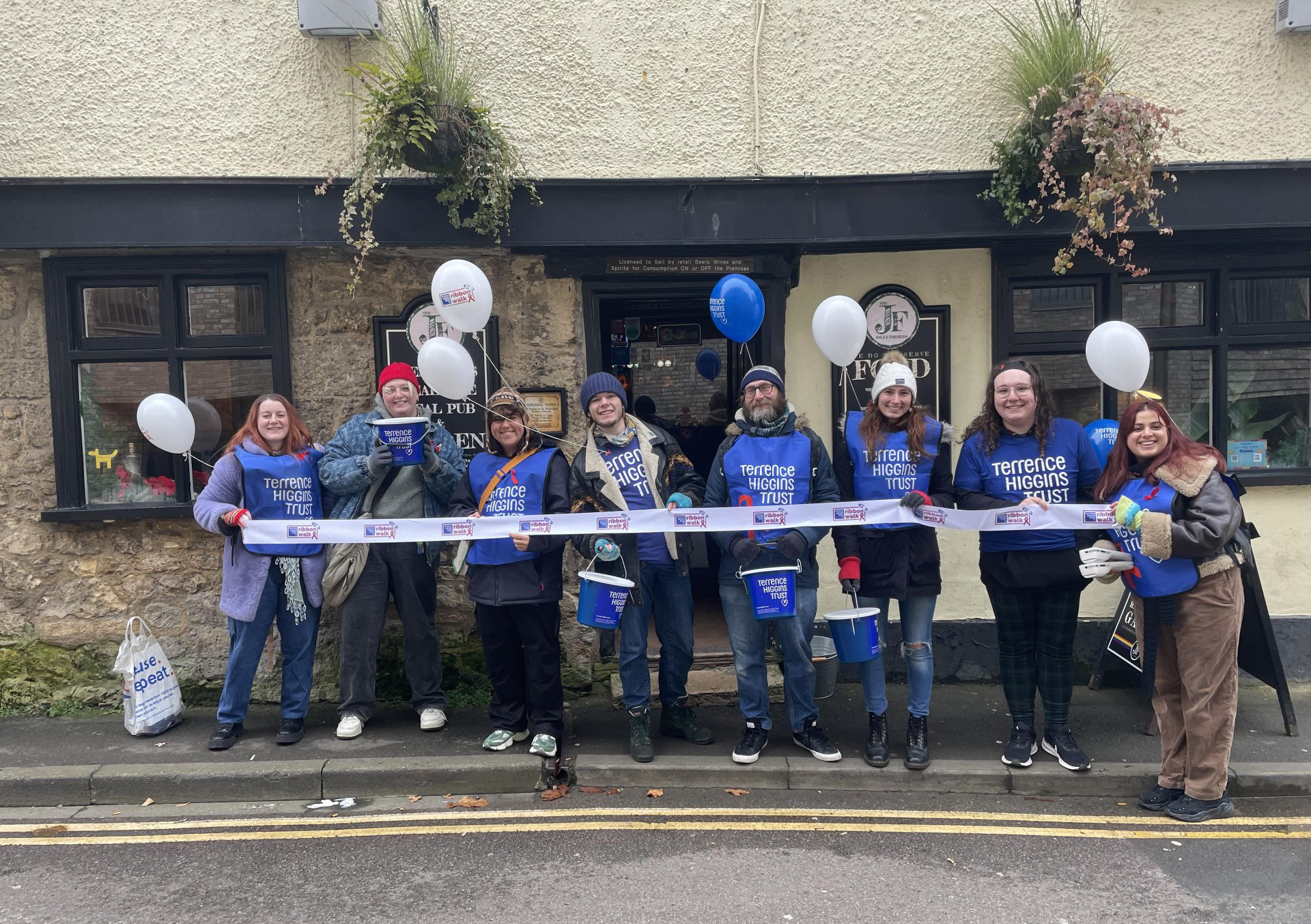 Line of people in THT shirts with balloons outside pub in Oxford