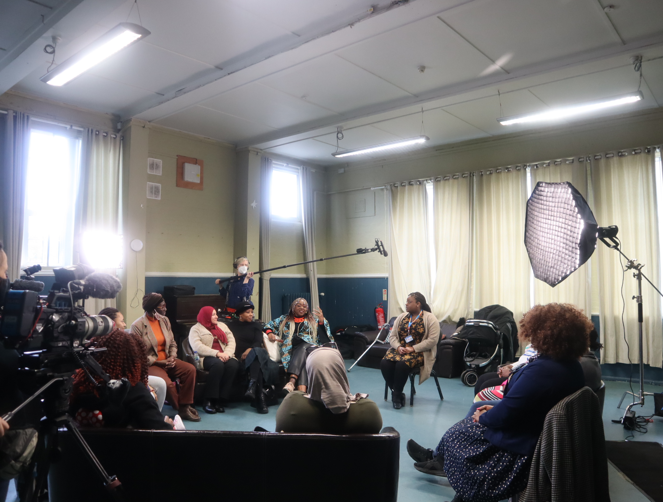 Image of a group of women of Black African and Caribbean heritage in discussion with a sexual health nurse. Recording equipment can be seen in the shot. 