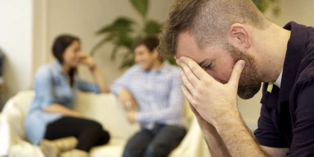 Man with head in his hands in front of couple of sofa