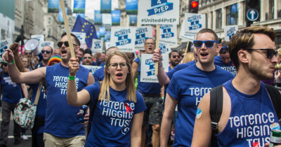 Terrence Higgins Trust staff and volunteers with banners and signs marching during Pride