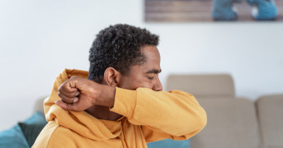 Man coughing into arm